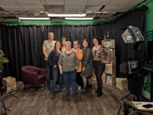 Groupe de sept personnes posant dans le studio podcast aux rideaux noirs