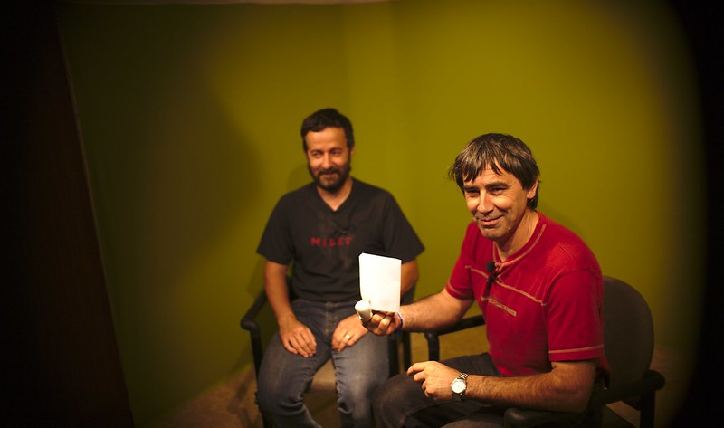 Septembre 2010, Alain Viard, premier président de l'association, donne une interview dans le studio à fond vert, un collègue souriant assis derrière lui.