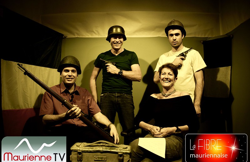 Juin 2010, ambiance dans le studio de Maurienne TV et La Fibre Mauriennaise : quatre membres de l'équipe posent en costume pour une mise en scène, casques et armes factices, devant les logos des deux structures.