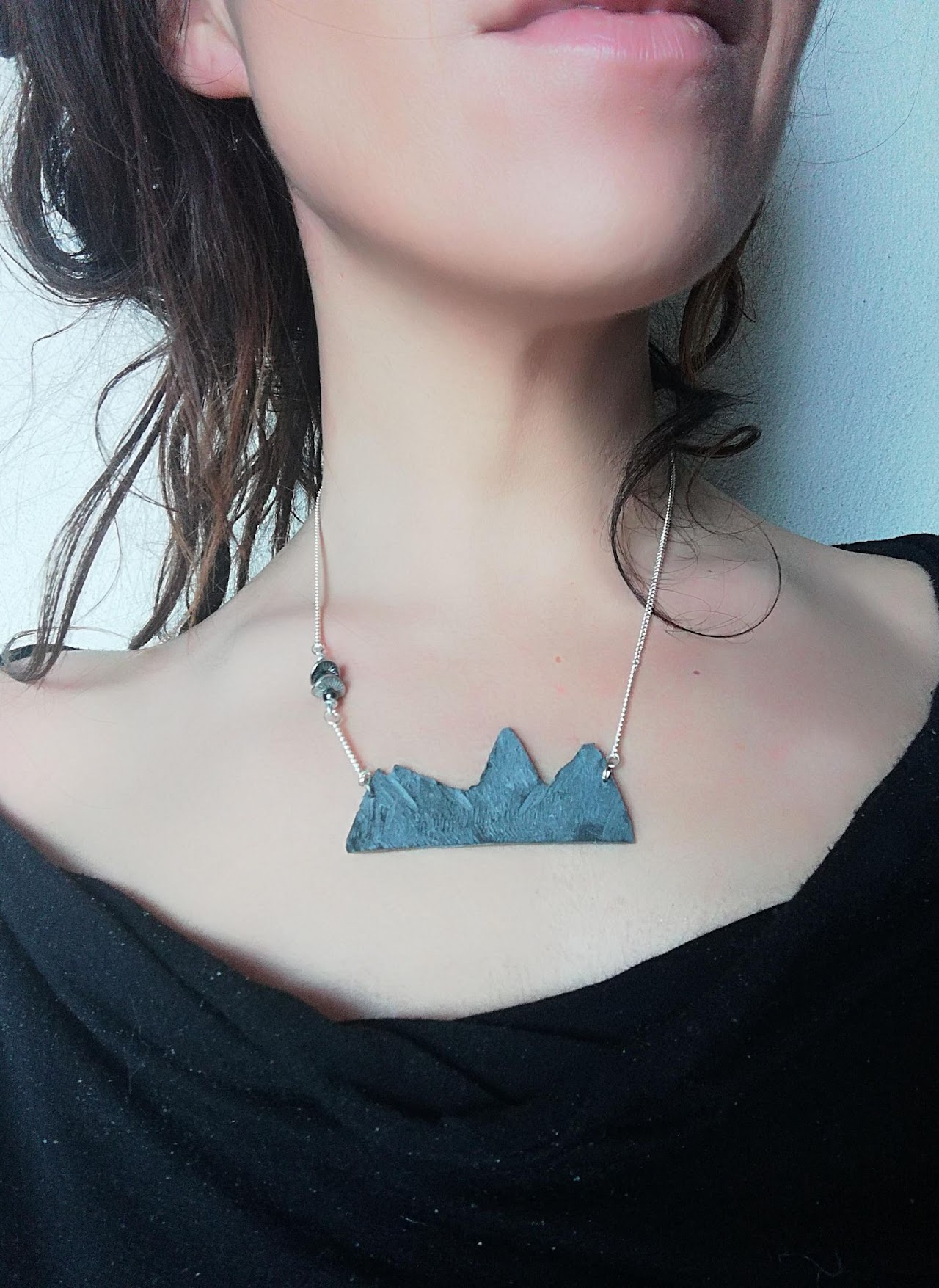 2018, collier artisanal en ardoise représentant la silhouette des Aiguilles d'Arves, porté autour du cou.