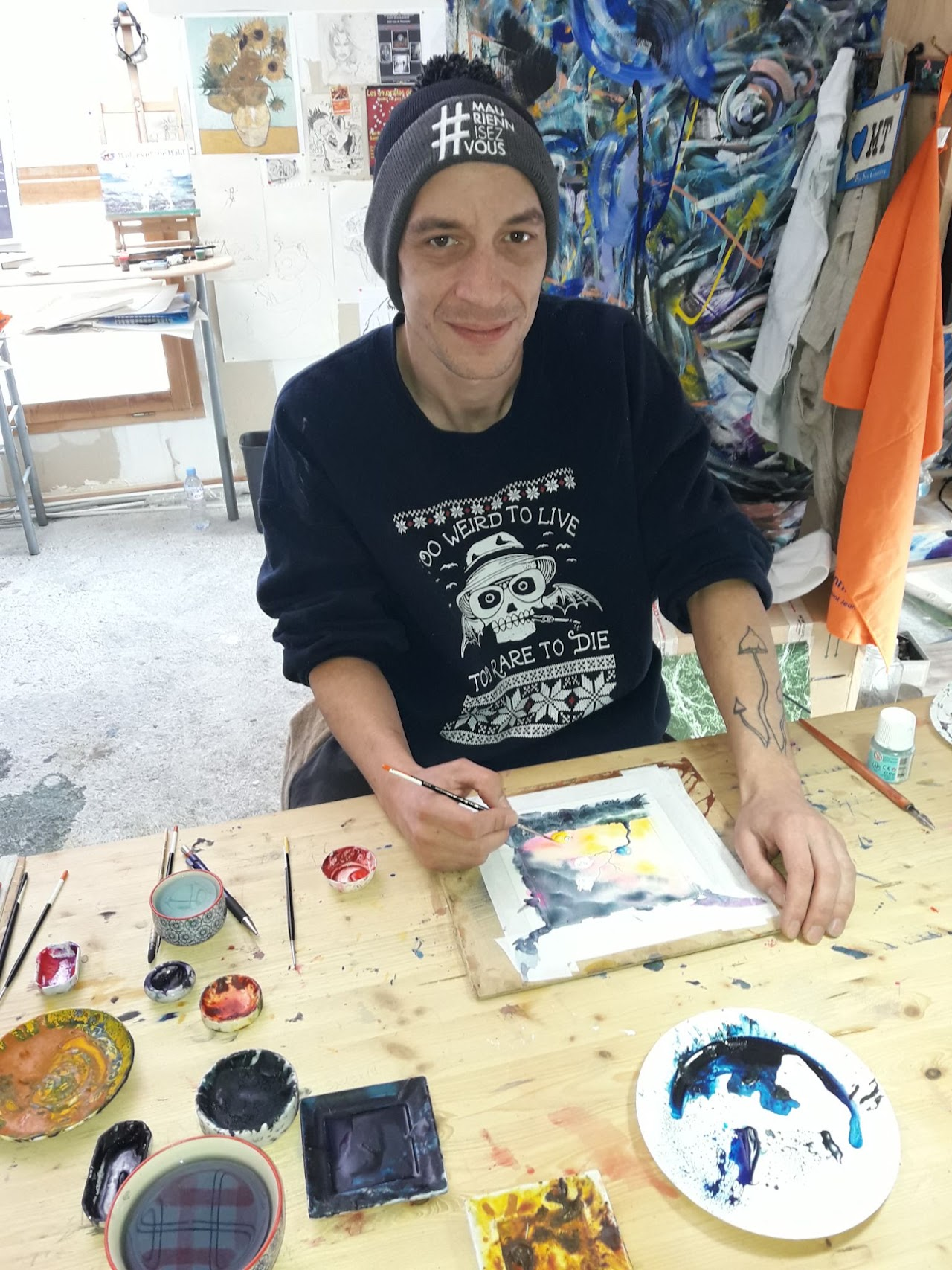 2018, un artiste peint dans son atelier, portant un bonnet #MauriennisezVous.