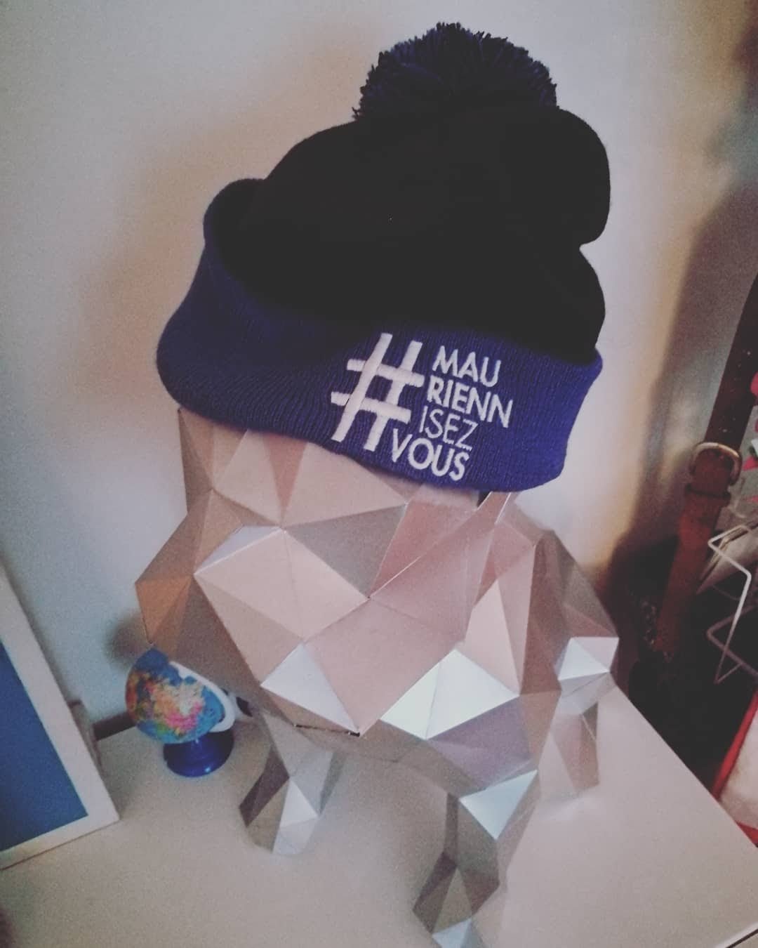 2018, un bonnet #MauriennisezVous posé sur une sculpture en papier géométrique.