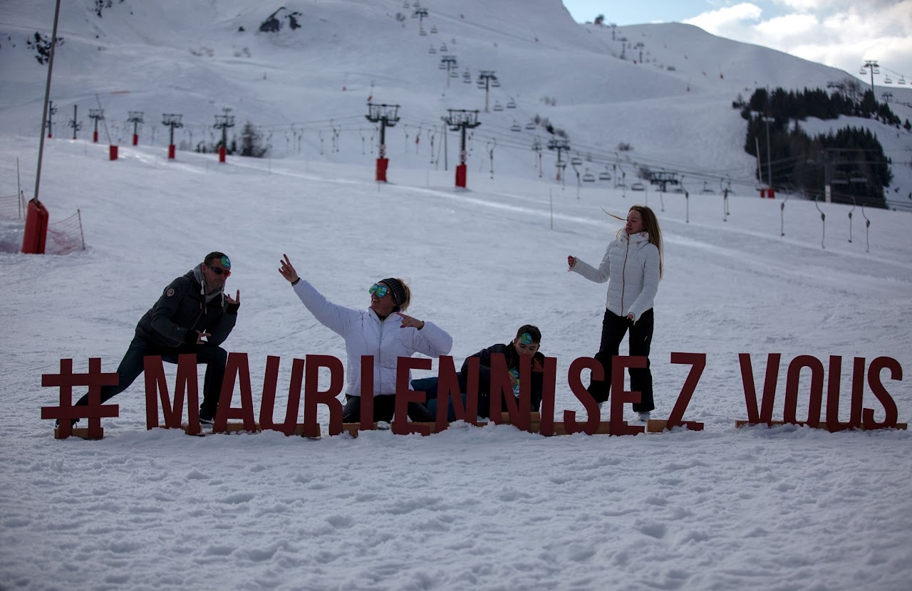 2018, quatre personnes posent avec les lettres géantes #MauriennisezVous plantées dans la neige, à La Toussuire.