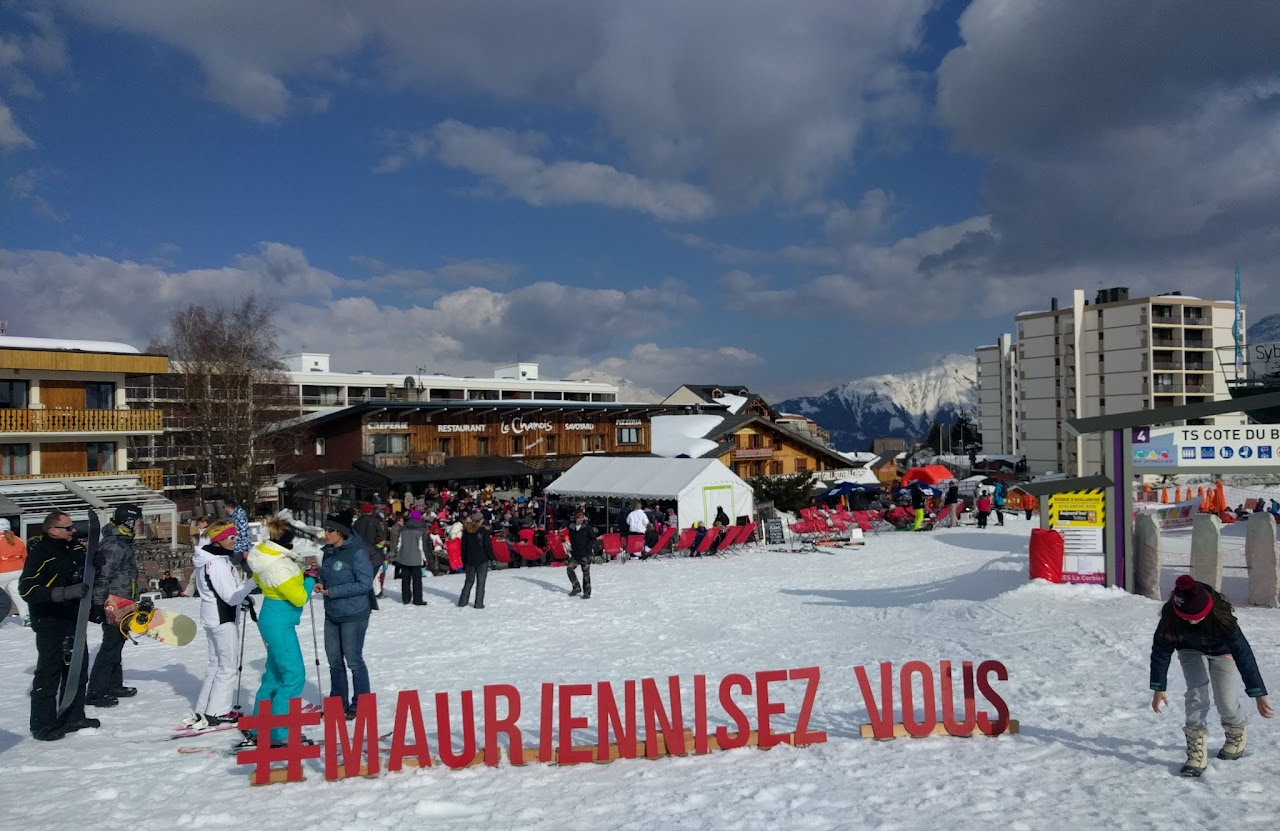 2018, vue large de La Toussuire avec les lettres géantes #MauriennisezVous dans la neige, restaurant Le Chamois en arrière-plan.