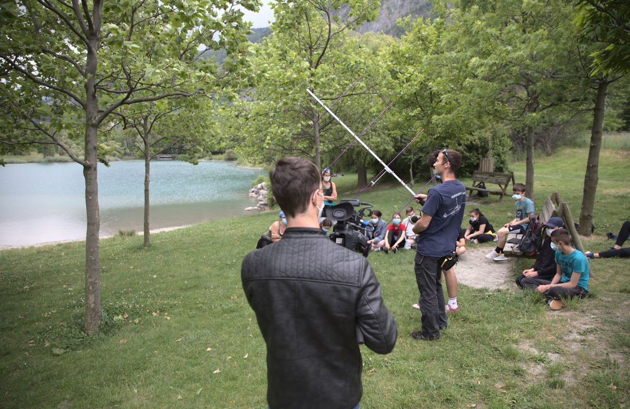 2021, démonstration de radio amateur en direct devant des collégiens au bord d'un lac, en référence au Général Ferrié, un membre de l'équipe manipule une antenne, un cameraman filme la scène.