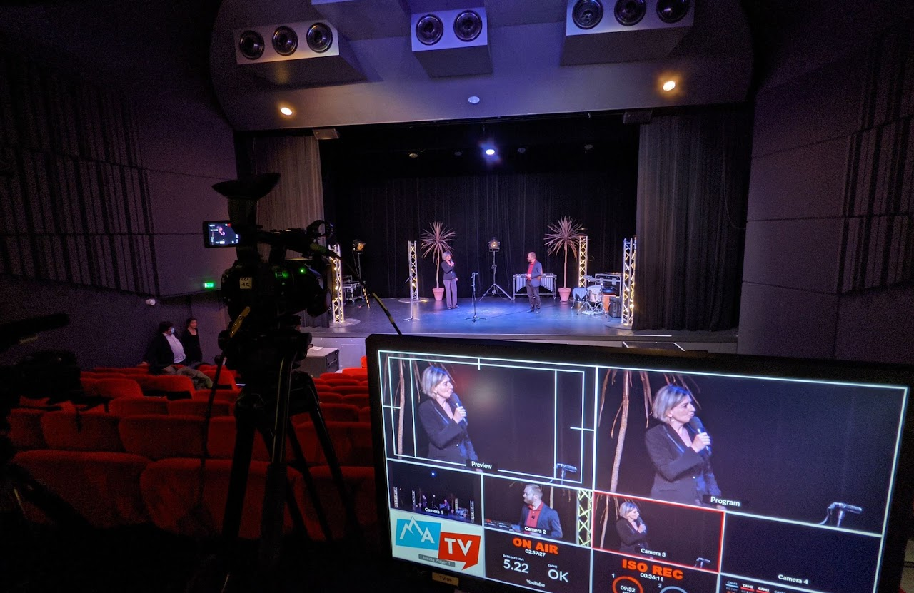 2021, régie vidéo multi-caméras dans la salle du théâtre vide, moniteur de retour affichant la présentatrice sur scène, pendant l'émission en direct sans public.