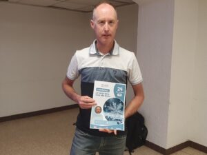 Frédéric Gaufillet, géophotographe, tient l'affiche de sa conférence « La neige dans tous ses états » à Saint-Jean-de-Maurienne