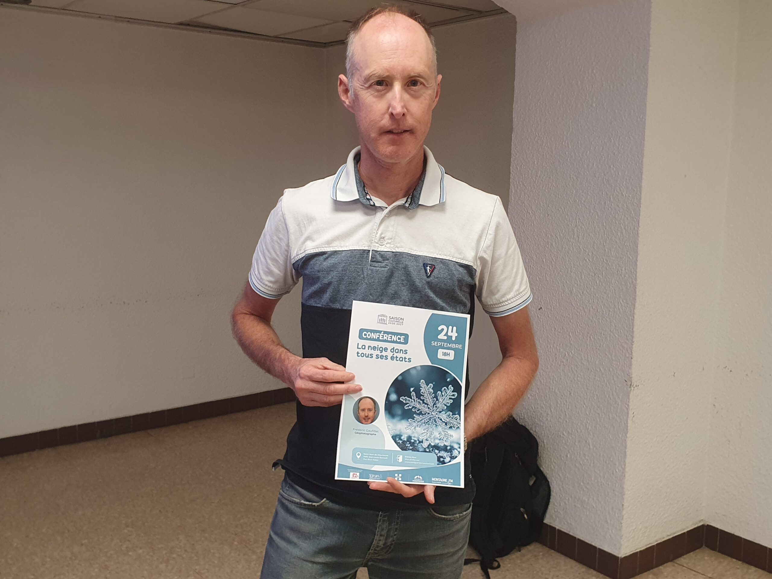 Frédéric Gaufillet, géophotographe, tient l'affiche de sa conférence « La neige dans tous ses états » à Saint-Jean-de-Maurienne