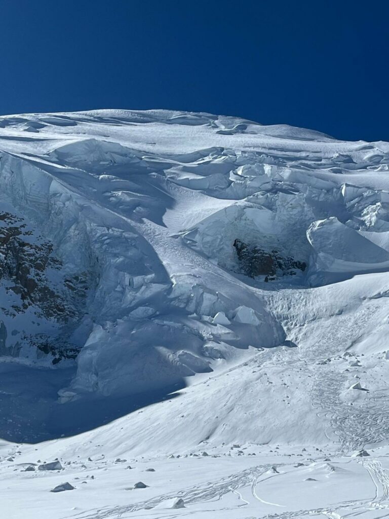 Un glacier aux séracs et aux crevasses, sous un ciel bleu profond