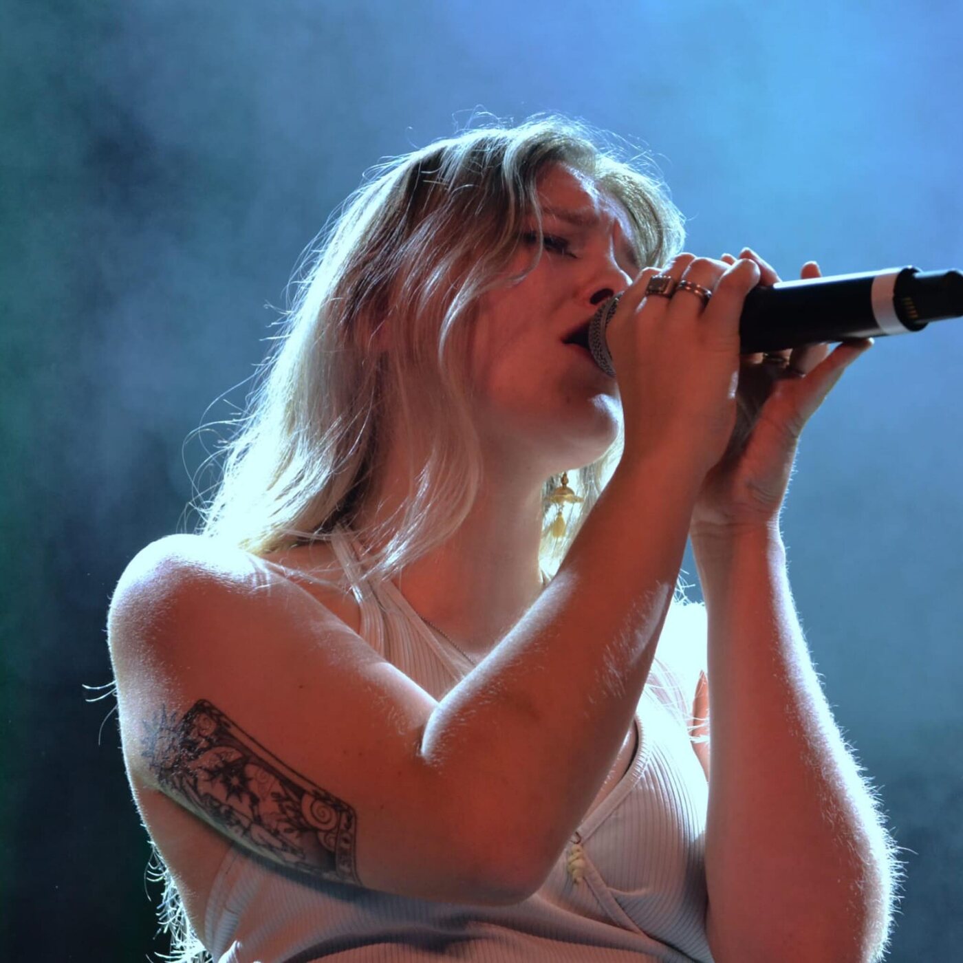La chanteuse du groupe stéphanois 404 en concert, les deux mains serrées sur le micro, dans la lumière bleue de la scène