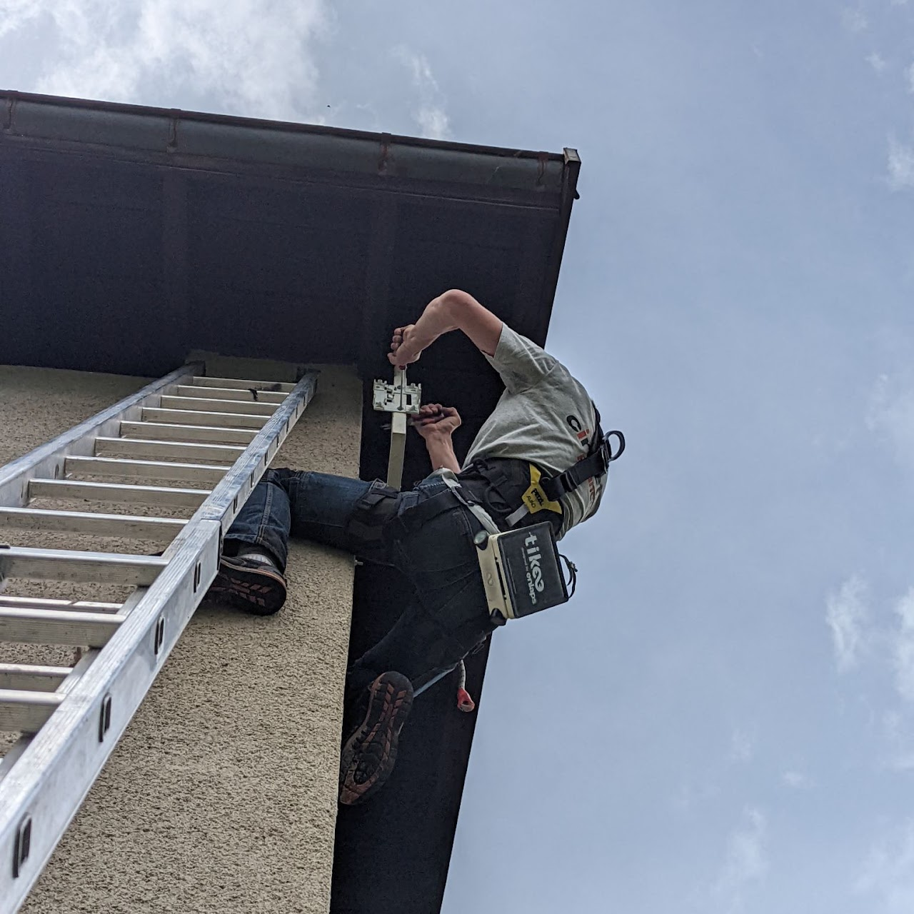 2022, un technicien encordé installe le boîtier de la webcam sur la façade d'un bâtiment, à Saint-Jean-de-Maurienne.