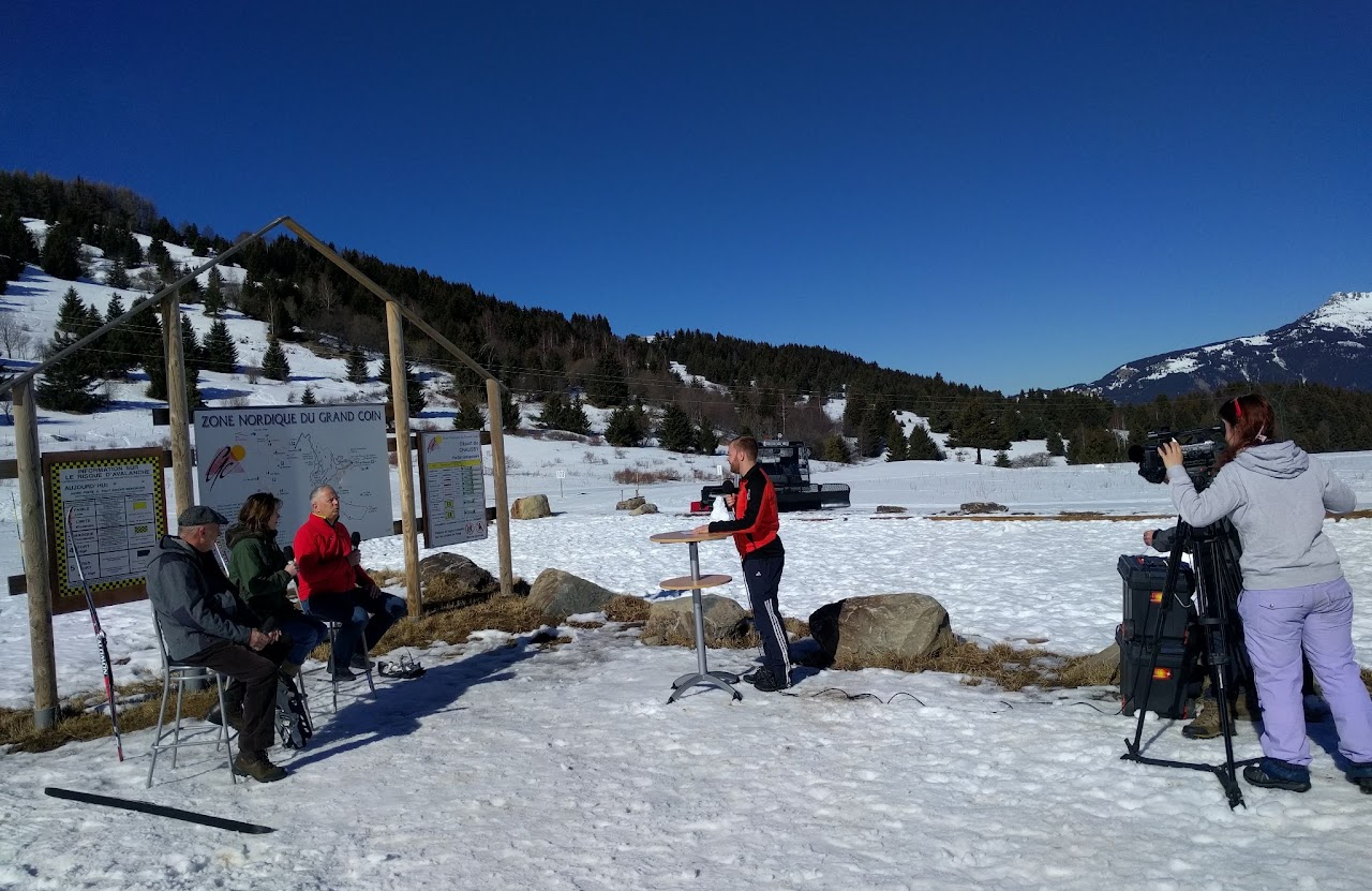 2017, Cédric en interview à la zone nordique du Grand Coin, au col du Chaussy, aux côtés de deux personnes assises et d'une caméramane.