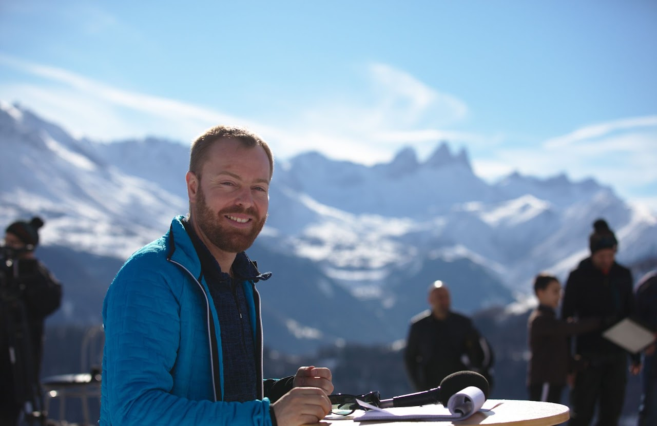 2017, Cédric souriant en interview en extérieur, les Aiguilles d'Arves enneigées en arrière-plan.