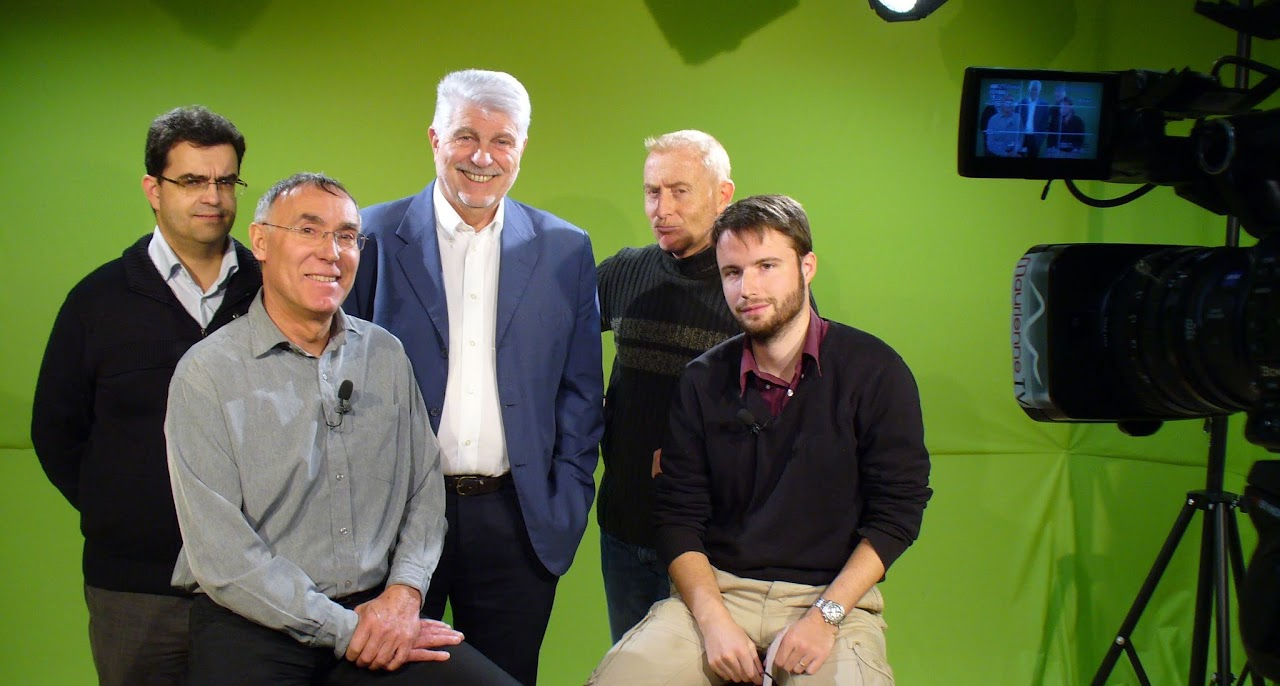Juin 2010, cinq membres de l'équipe posent dans le studio à fond vert autour d'une interview avec Jean-Claude, Manu en coulisse et Gib, caméra « Maurienne TV » au premier plan.