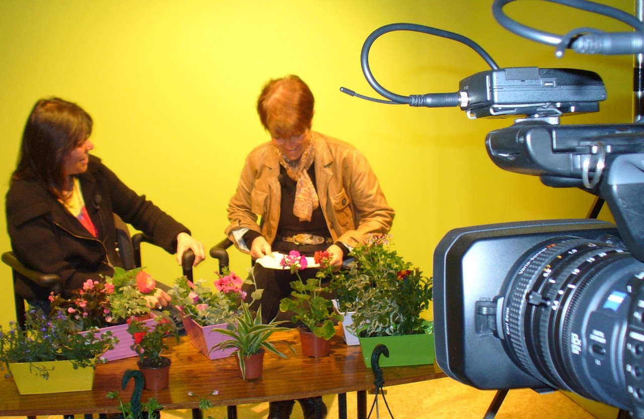 2011, Pascale interviewe une invitée devant une table couverte de plantes en pot, dans le studio, caméra au premier plan.