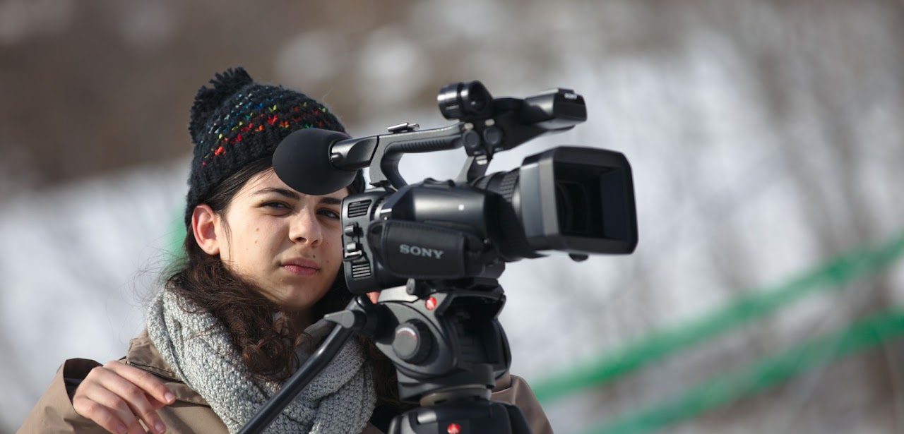 2017, Mareva derrière la caméra, bonnet et écharpe, en extérieur sur la neige.