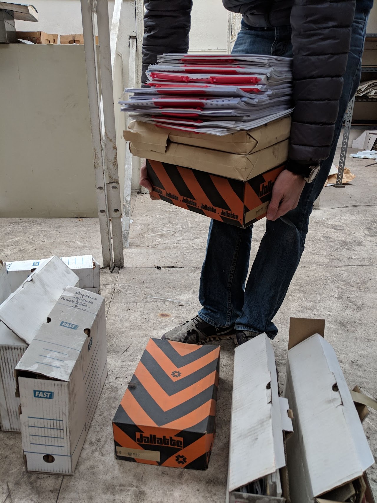 2018, un bénévole porte des cartons d'archives (registres, dossiers) lors du sauvetage des archives à MetalTemple.