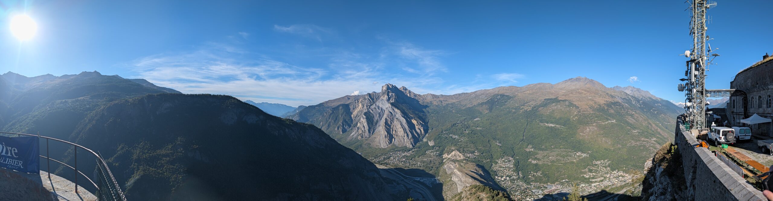 Vue panoramique depuis le Fort du Télégraphe sur la vallée de la Maurienne et ses montagnes, avec le pylône d'antennes de télécommunications à droite et des véhicules garés au premier plan