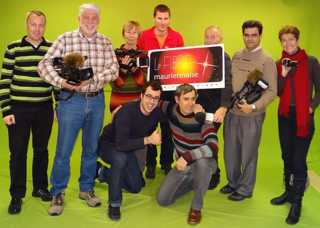 Photo de groupe de l'association en décembre 2012, dans le studio à fond vert, autour de la banderole La Fibre Mauriennaise, caméras à la main.