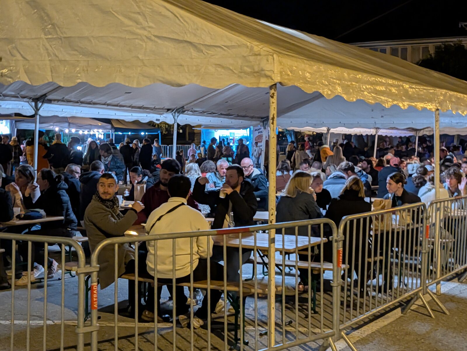 Des centaines de festivaliers attablés sous les chapiteaux de la Punta Octobeer 2025 à Modane, verre en main, dans l'ambiance d'une soirée de fête en plein air