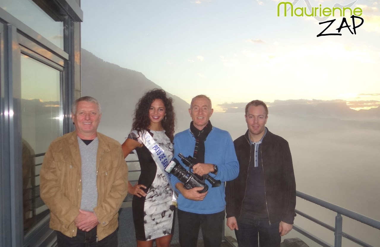 2013, tournage à Aiton avec Cédric : quatre personnes posent en terrasse au coucher du soleil au-dessus d'une mer de nuages, dont Miss Pays de Savoie en écharpe, logo Maurienne Zap.