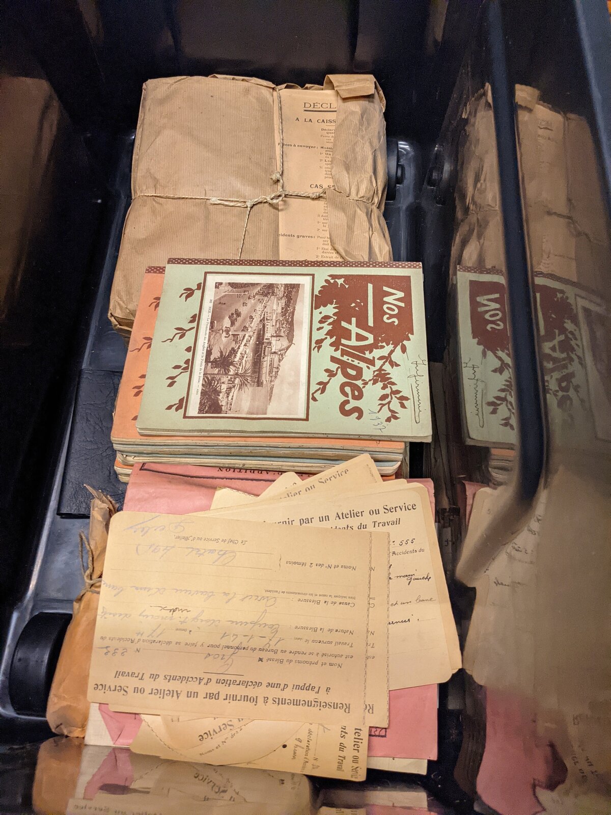 Liasses de papiers anciens ficelées, dont une revue « Nos Alpes », dans un bac lors du déplacement des archives en octobre 2021