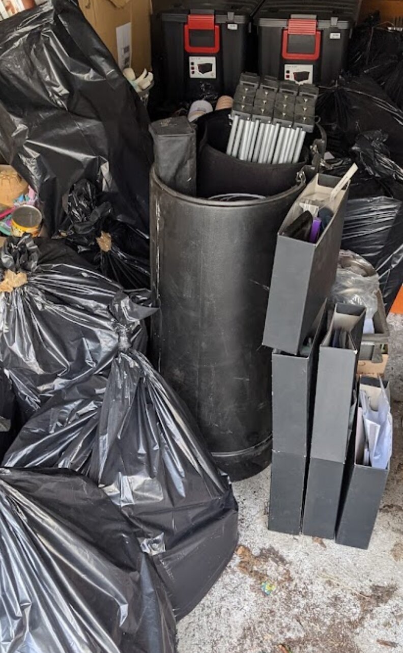 Sacs-poubelle, bacs et boîtes d'archives de Métal Temple entreposés dans un garage