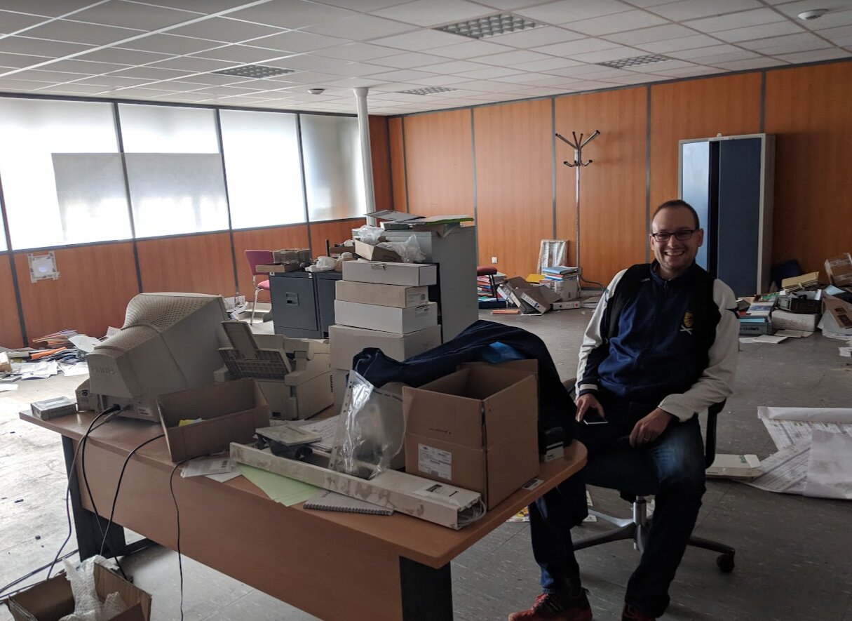 Florian, bénévole, assis à un bureau encombré de cartons d'archives et d'un vieil écran dans l'usine Métal Temple