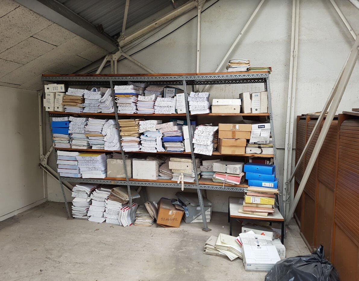 Étagère métallique chargée de dossiers et de classeurs d'archives dans un local de l'usine Métal Temple