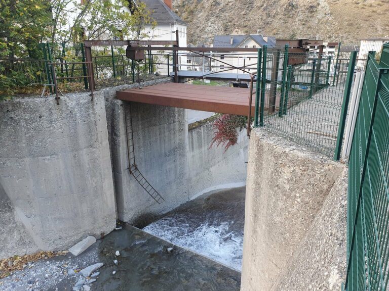 Passerelle métallique au-dessus du chenal bétonné du torrent du Charmaix, une échelle fixée à la paroi et l'eau qui s'écoule au fond