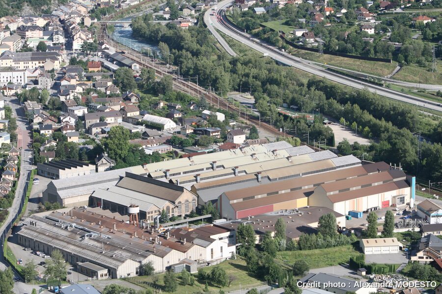 Vue aérienne de 2007 des usines FORMER et Métal Temple à Saint-Michel-de-Maurienne : grands bâtiments industriels, voie ferrée et autoroute